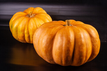 Two whole fresh orange big pumpkin on black background, closeup. Organic agricultural product, ingredients for cooking, healthy food vegan.