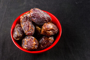 Big luxury dried date fruit in bowls on the dark surface, kurma ramadan kareem concept, close up.