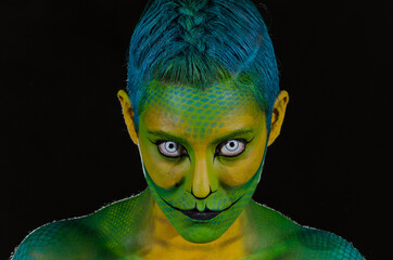 Retrato de mujer joven maquillada bodypaint reptil en fondo negro