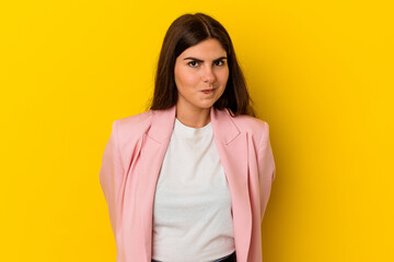 Young caucasian woman isolated on yellow background shrugs shoulders and open eyes confused.
