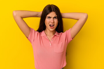 Young caucasian woman isolated on yellow background screaming with rage.