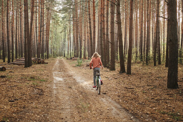 Obraz premium Caucasian teenage girl faceless on a bicycle rides in the forest. Relaxation and wellness concept.