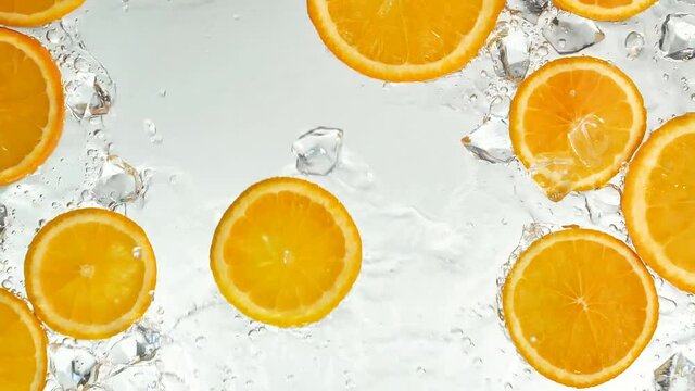 Oranges being doused with water, top view. Slow motion.