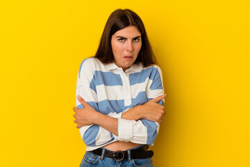 Young caucasian woman isolated on yellow background shrugs shoulders and open eyes confused.
