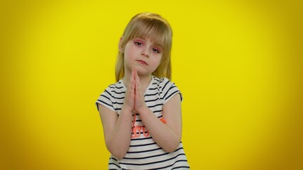 Please, God, forgive and help me. Child girl 5-6 years old sincerely praying to God and looking up with pleading expression, begging apology, beseeching with hopeful face. Teen kid children on yellow