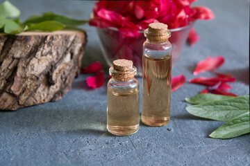 Glass bottles with oil or tincture on a background with wood and petals. Natural cosmetics and spa concept