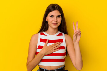 Young caucasian woman isolated on yellow background taking an oath, putting hand on chest.