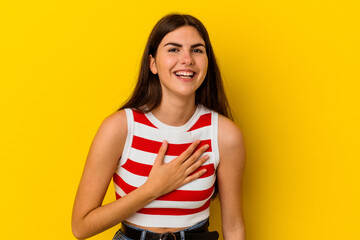 Young caucasian woman isolated on yellow background laughs out loudly keeping hand on chest.