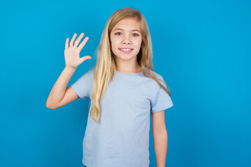 Fototapeta na wymiar beautiful Caucasian little girl wearing blue T-shirt over blue background showing and pointing up with fingers number five while smiling confident and happy.