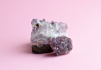 Beautiful druses of natural purple mineral amethyst  on a pink background. Large crystals of...