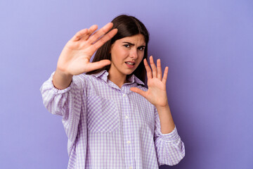 Young caucasian woman isolated on purple background being shocked due to an imminent danger