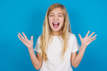 Crazy outraged beautiful Caucasian little girl wearing white T-shirt over blue background screams loudly and gestures angrily yells furiously. Negative human emotions feelings concept