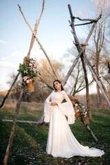 Fototapeta premium A beautiful bride in a light dress poses. Boho style. 