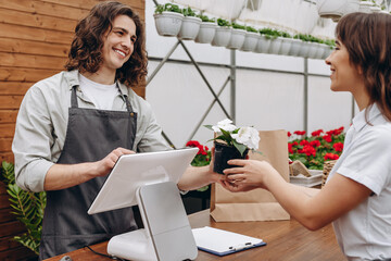 Gardening, planting concept. Pretty woman buy houseplant in greenhouse or garden center.
