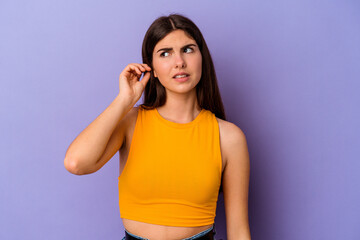 Young caucasian woman isolated on purple background covering ears with fingers, stressed and desperate by a loudly ambient.