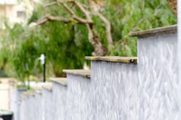 Detail of a house, boundary wall: in reinforced concrete. Step shape with wall painted in urban camouflage color.