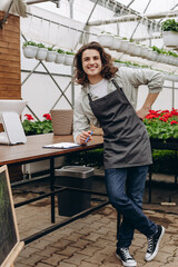 Portrait of happy male florist standing at his flower shop near cash register. Job concept.
