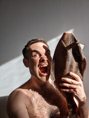 A joyful man with his mouth open holds a large halibut in his hand. Concept of marine food, libido,...