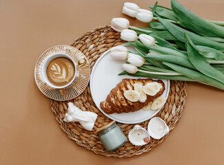 Mothers Day, 8 march,  Good morning. White Fresh Tulips, Coffee cup and croissant on brown background, top view, flat lay