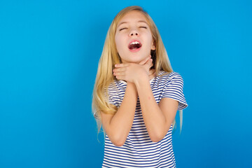 Caucasian kid girl wearing striped shirt ​against blue wall  shouting suffocate because painful strangle. Health problem. Asphyxiate and suicide concept.