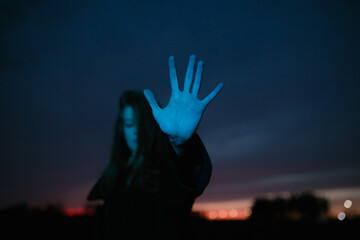 Girl with outstretched palm in the dark.