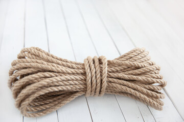 Fototapeta na wymiar Rope made of natural jute on a white wooden background.