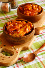 Chicken fillet with beans. Two wooden bowls with chicken stewed in tomato sauce. Serving the dish - 431810492