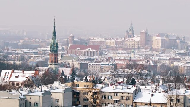 Panoramic footage of Wawel Royal Castle from Krakus Mound, the highest point in the city of Krakow, Poland. City skyline. Ancient buildings against the clear white sky in the background. 