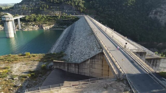 Toma en 4k vista de drone de un chico andando por una presa con la bandera de estados unidos