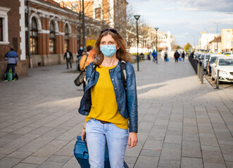 Fototapeta premium woman traveler with suitcase wearing mask