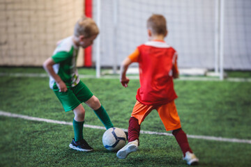 Football soccer game for kids, junior young football team group of children team having training session, or football game on a pitch, running and kicking ball on green pitch