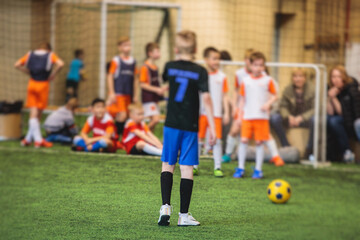 Obraz premium Football soccer game for kids, junior young football team group of children team having training session, or football game on a pitch, running and kicking ball on green pitch