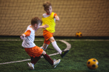 Football soccer game for kids, junior young football team group of children team having training session, or football game on a pitch, running and kicking ball on green pitch