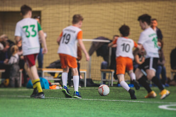 Football soccer game for kids, junior young football team group of children team having training session, or football game on a pitch, running and kicking ball on green pitch