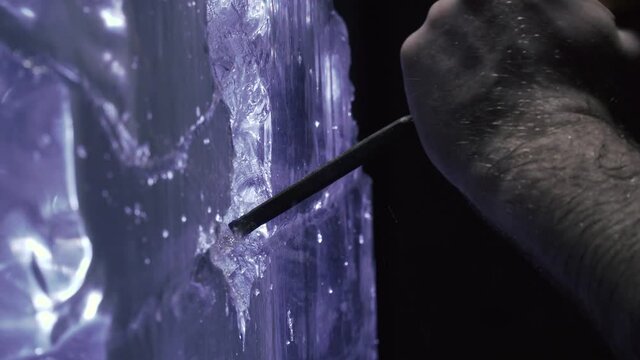 Close up of the artists hands while working with a chisel on an ice sculpture 4k