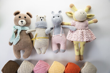Soft bright dolls made of yarn lie on a white background with balls of multi-colored yarn....