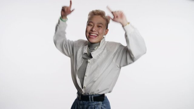 Confident young Asian person dances and poses for camera