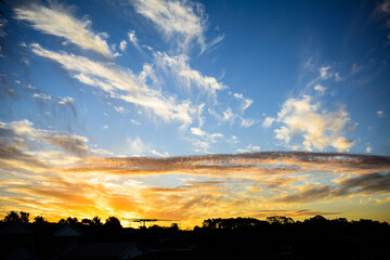 Bright blue and fiery orange sky with spindrift clouds during sunset