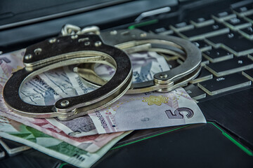 Handcuffs on paper money on keyboard in close-up