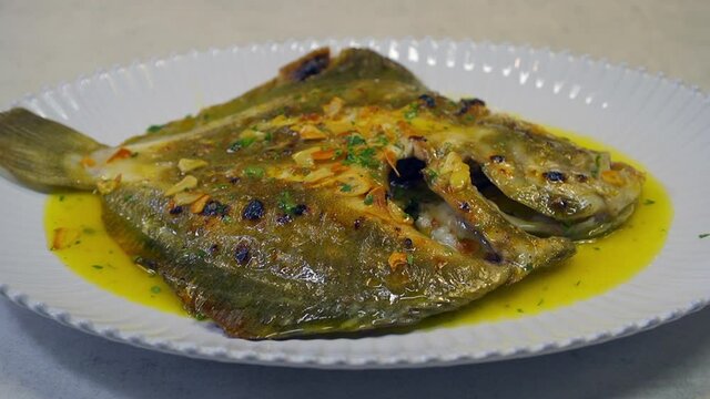 Grilled turbot with garlic and butter sauce, lemon and aromatic herbs