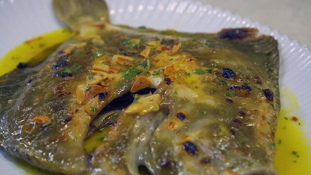 Grilled turbot with garlic and butter sauce, lemon and aromatic herbs