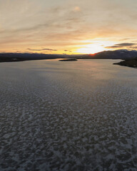 Portrait view of a northern Canadian sunset in April with bright orange hues. From a frozen lake in...