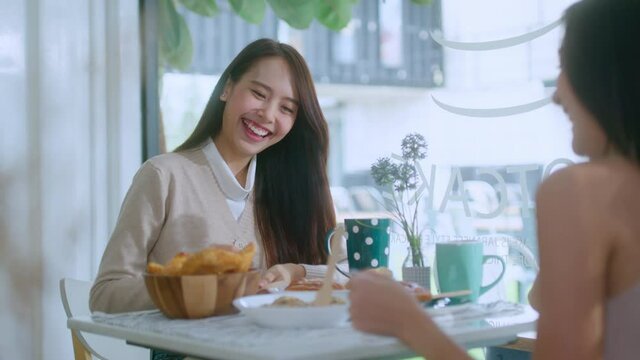 attractive asian female talking good positive conversation to friends with smiling laugh and happiness moment at counter near window at cafe with daylight from garden positive attitude relationship