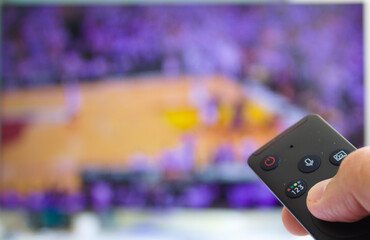 caucasian male watching television resting in the bed and switching channels virtual basketball...