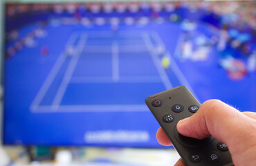 caucasian male watching television resting in the bed and switching channels virtual tennis game...