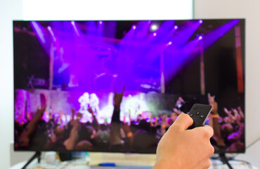 caucasian male watching television resting in the bed and switching channels virtual gig concert horns up