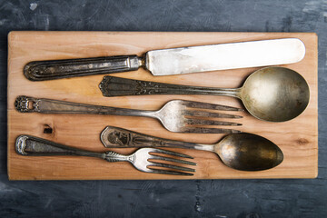 old cutlery on a cutting board. view from above.