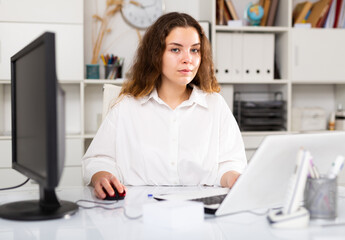 Portrait of young elegant confident female office worker in a company at a modern workplace