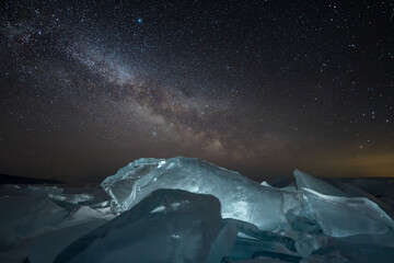 Night stars milky way time lapse at lit big blue ice blocks. Baikal lake in winter time.