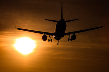 夕陽に向かって飛ぶ飛行機のシルエット